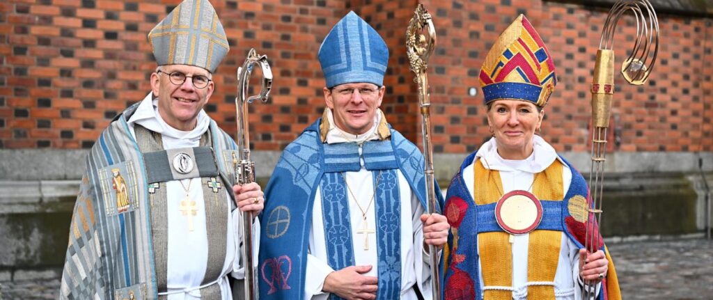 nya biskoparna Erik Eckerdal och Marika Markovits tillsammans med ärkebiskop Martin Modéus utanför Uppsala domkyrka.